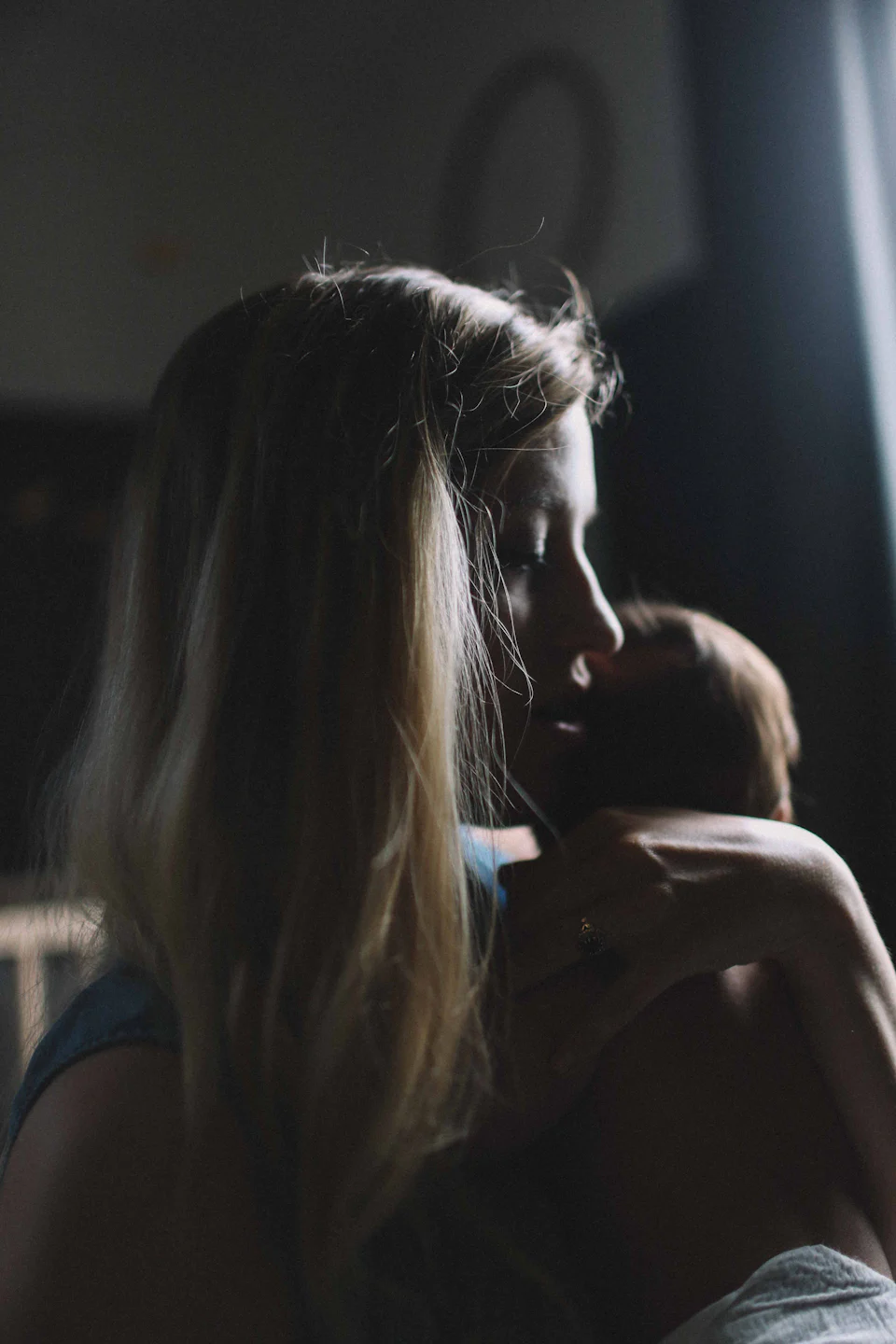 Eine Mutter hält ihr Baby in einem dunklen Zimmer nah bei sich.